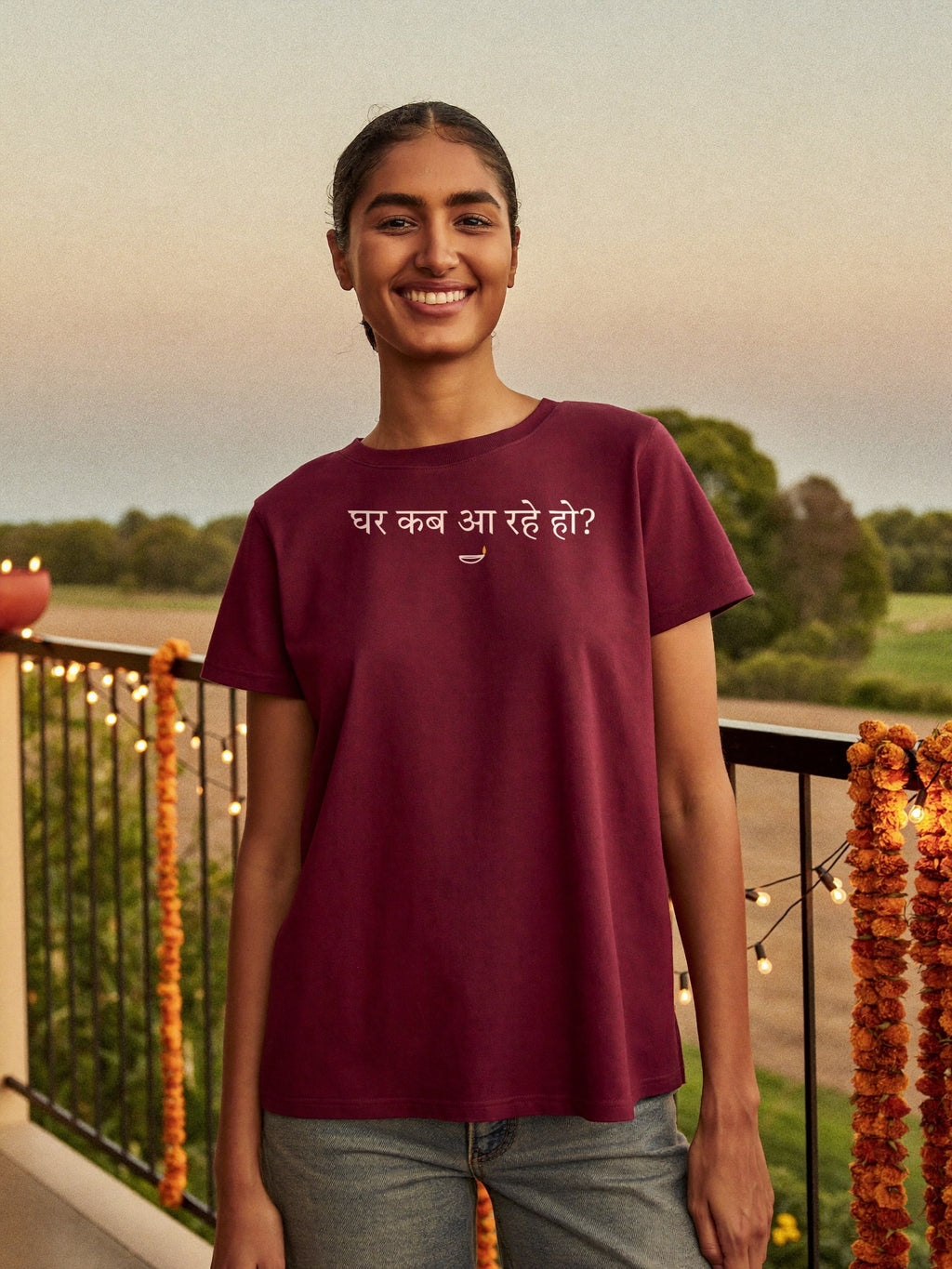 Woman wearing the “घर कब आ रहे हो?” Hindi Diwali t-shirt with diya in maroon by Halant, diwali balcony